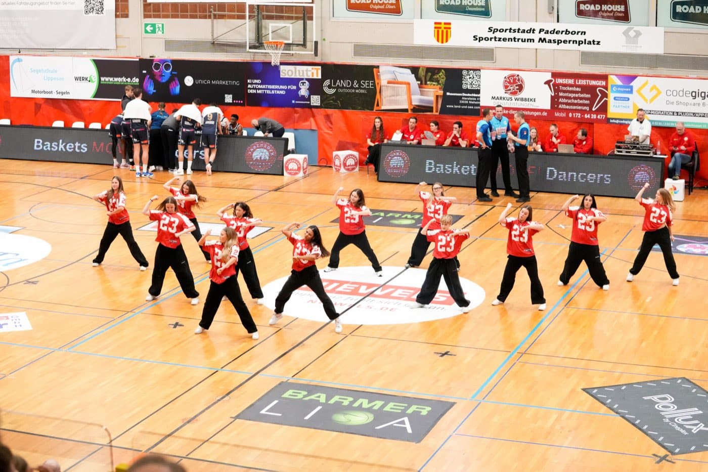 Die Baskets Dancers tanzen in roten Trikots auf dem Spielfeld